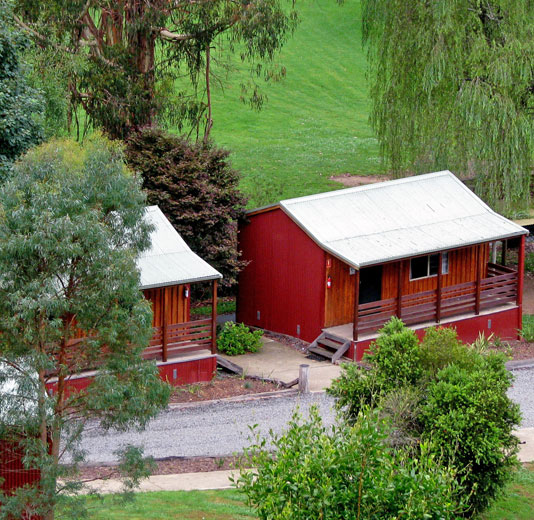 McKerlie Creek Cabins - red wooden cabins in a grassy setting